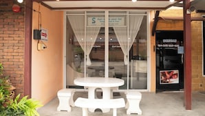 An outdoor seating area with a table and benches, a brick wall, and a glass door entrance.