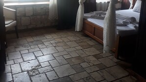 A room with a bed, a window with curtains, a stone wall, and a tiled floor. - Kekova Restaurant & Pansiyon (Demre)