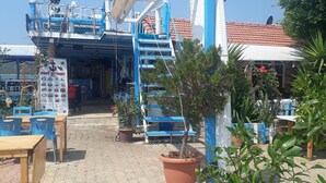 A restaurant with outdoor seating, a satellite dish, and potted plants. - Kekova Restaurant & Pansiyon (Demre)