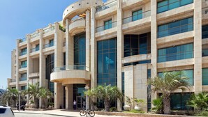 A modern building with multiple floors, large windows, and a curved entrance. - Laguna Water Front 1 (Herzliya)