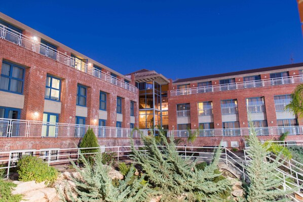 A multi-story building with a brick facade, balconies, and a central open area with stairs.