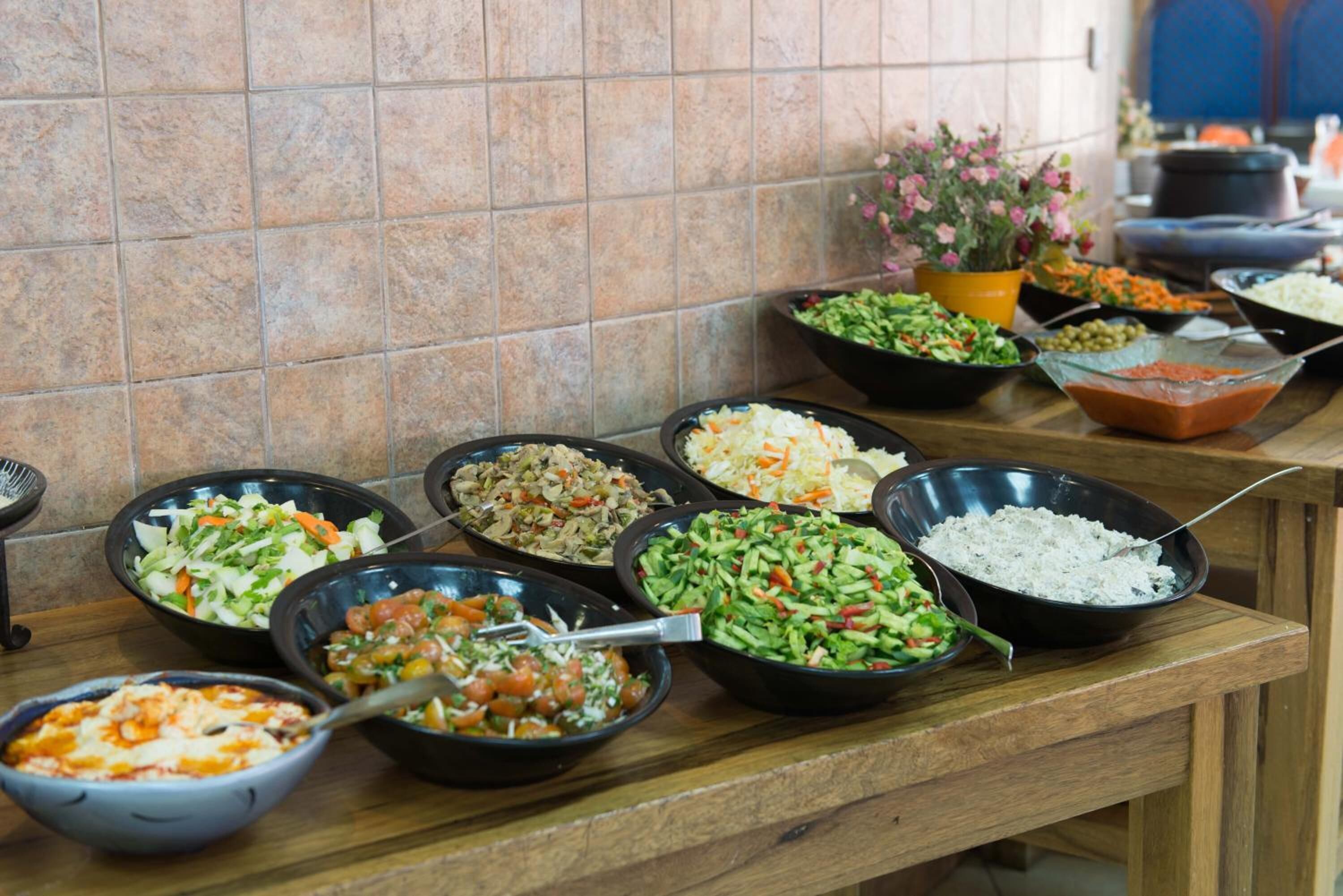 Una mesa de buffet con diversos platos, entre ellos ensaladas, arroz y un bol de sopa.