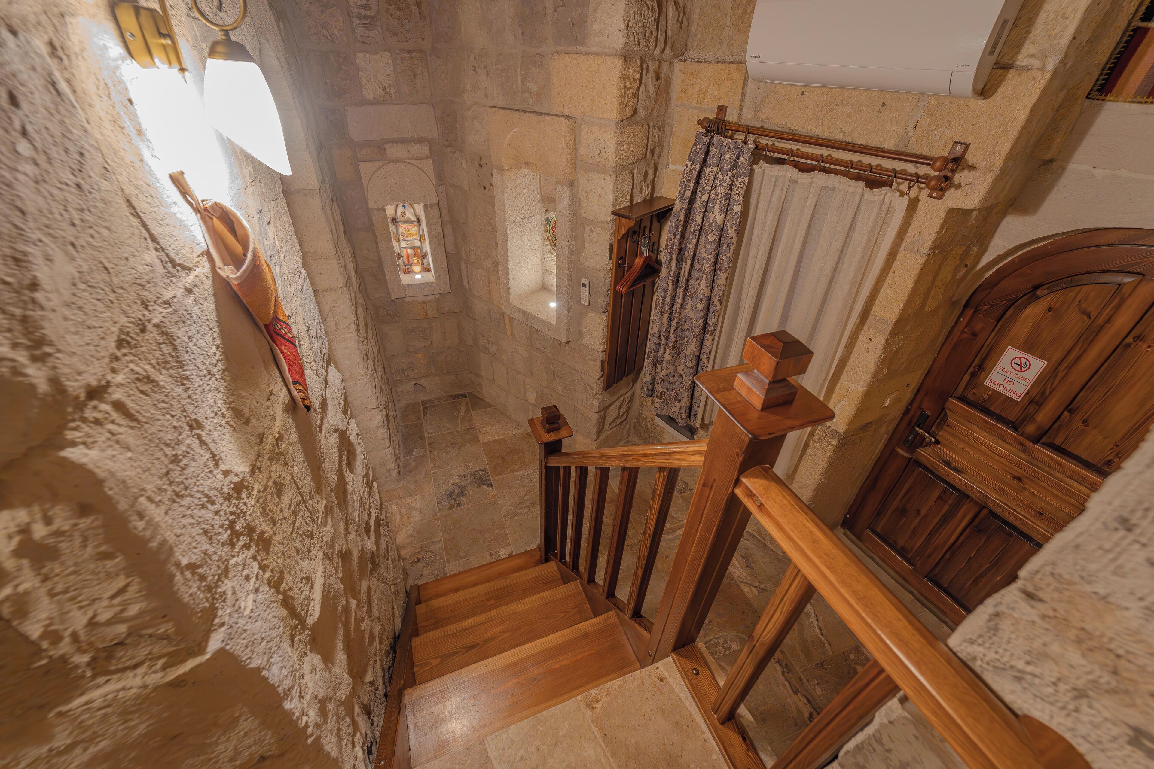 Un escalier en bois, des murs en pierre et une porte en bois avec une enseigne.