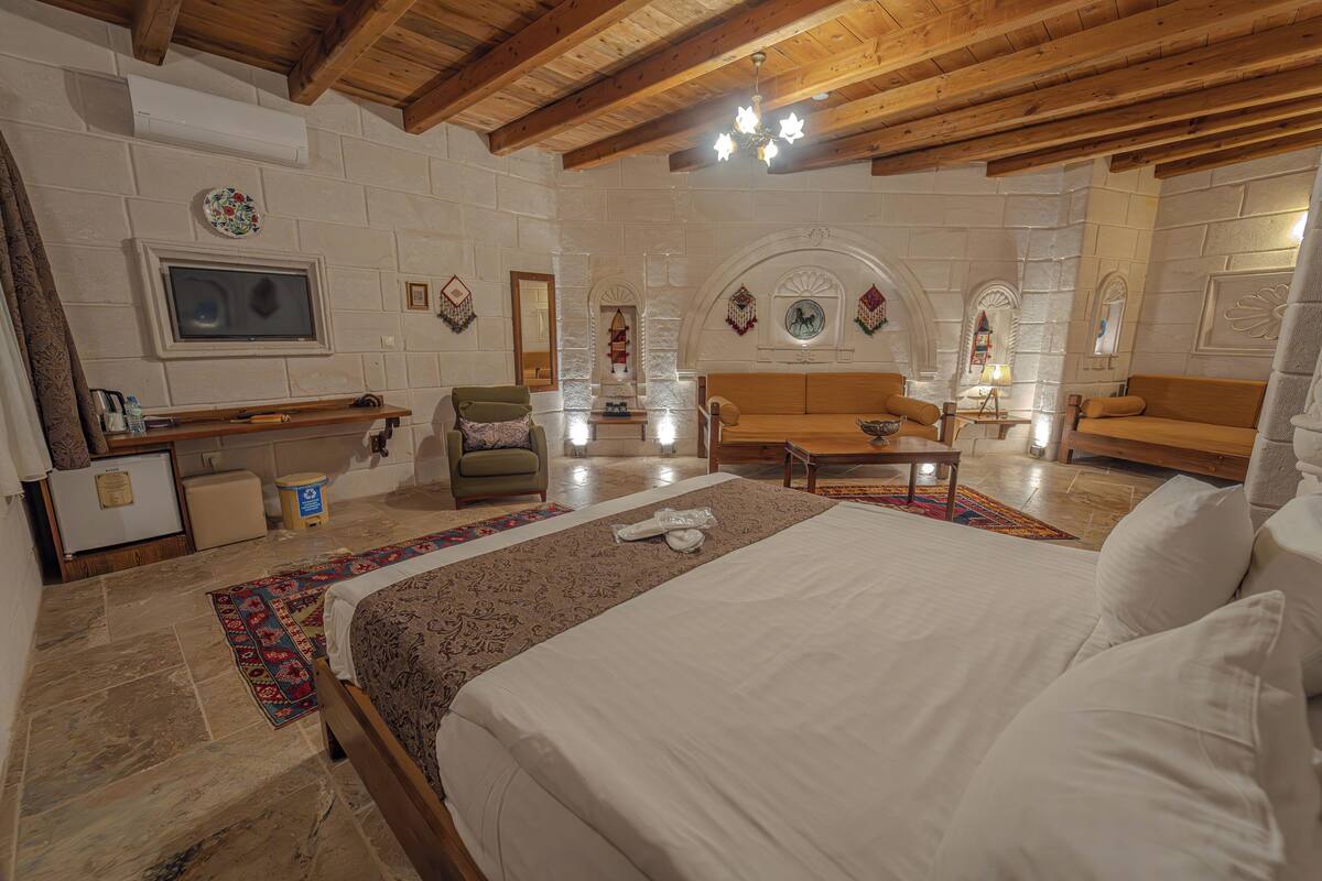 Une chambre spacieuse avec un grand lit, un plafond en bois et un mur en pierre.