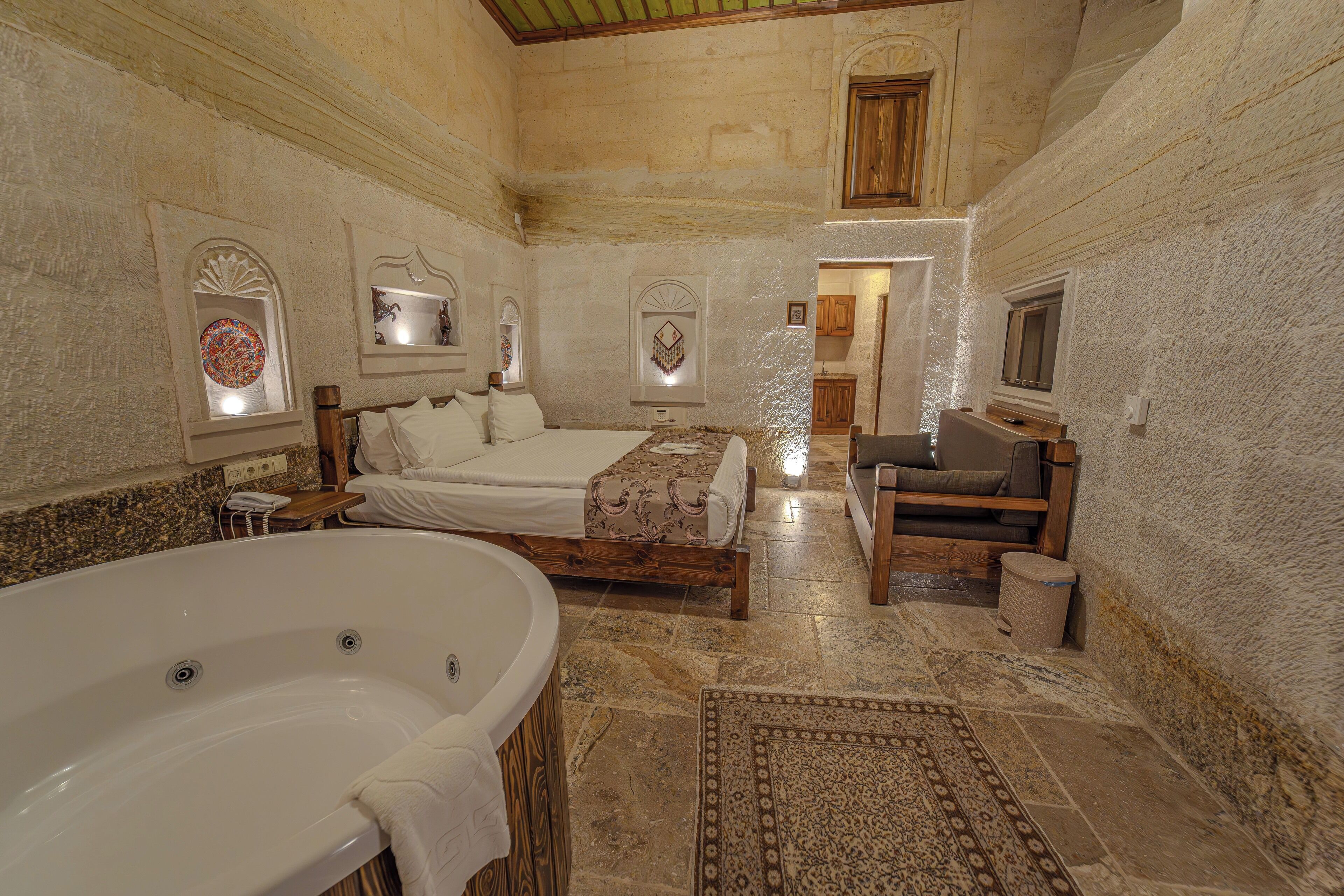 A spacious bathroom with a large bathtub, a wooden bench, and a patterned rug.