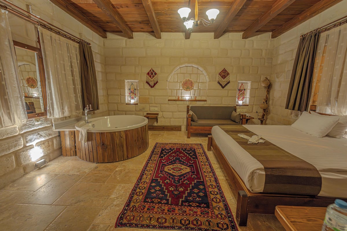 Une chambre avec un grand lit, une baignoire en bois, un canapé et un tapis.