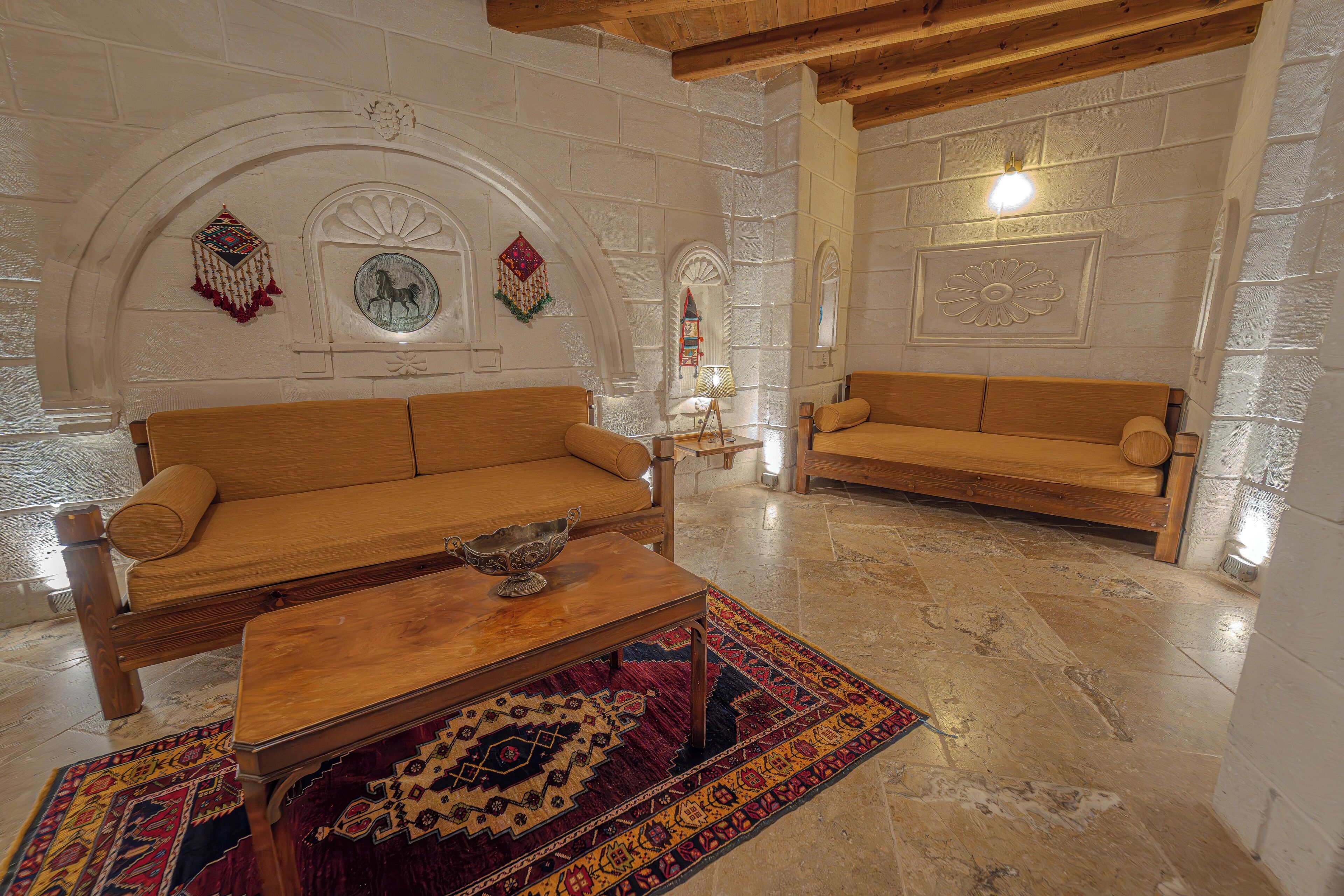 A room with two wooden sofas, a wooden coffee table, and a patterned rug.