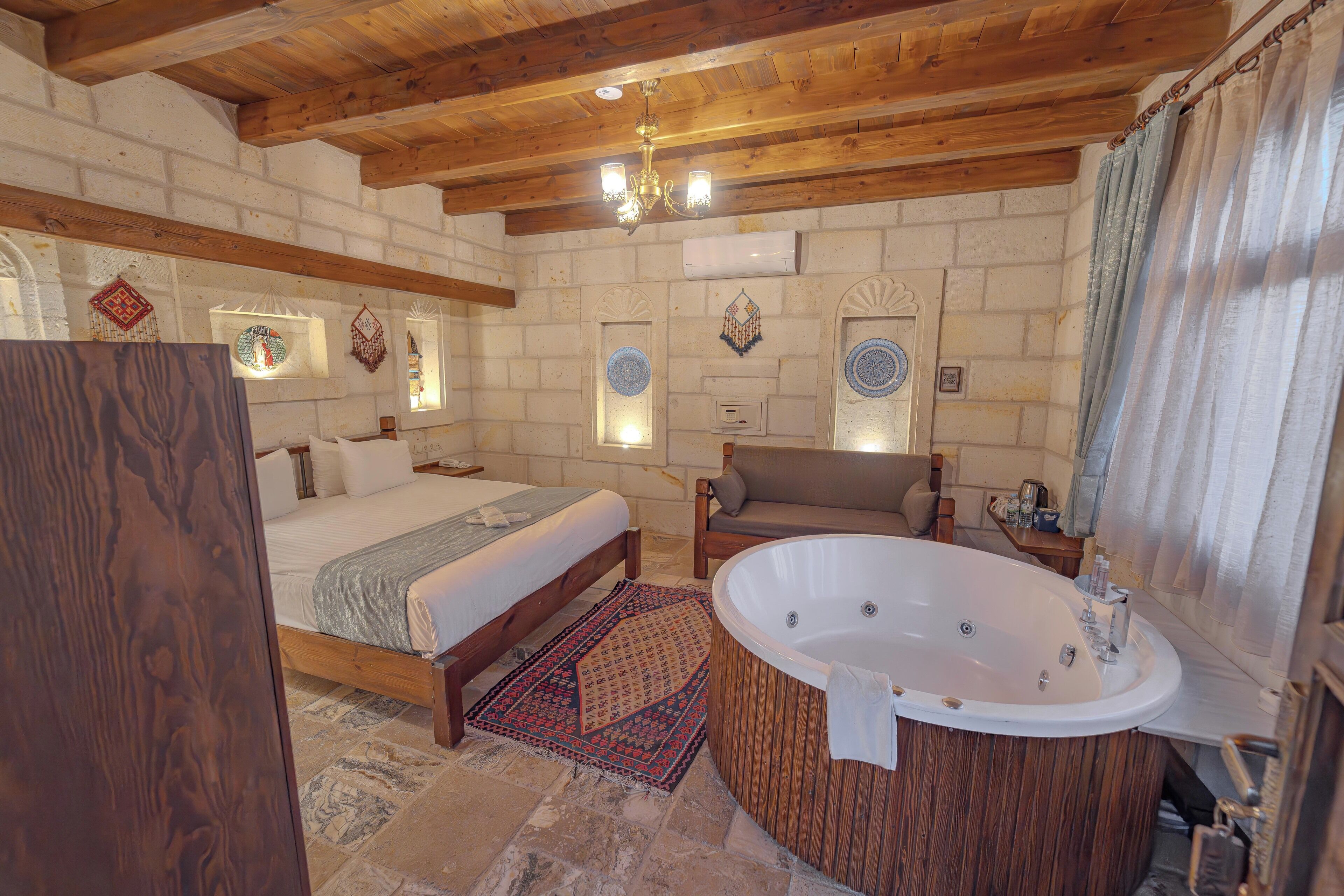 A bedroom with a large bed, a wooden bathtub, and a stone floor.