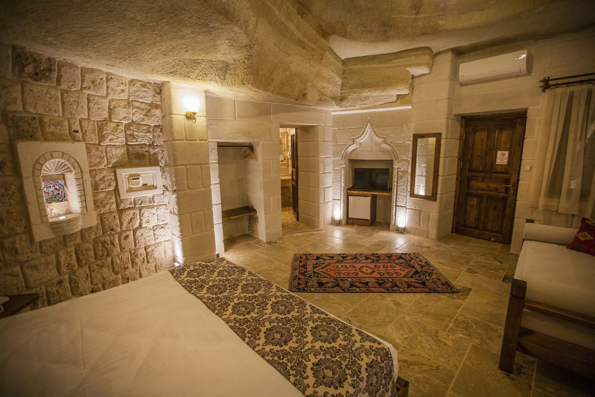 Une pièce aux murs de pierre, avec une cheminée, un lit et un canapé.