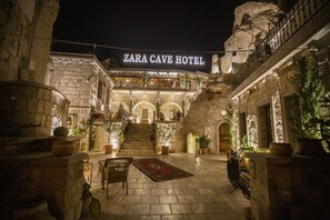 Hotel Cueva Zara, con arquitectura de piedra, una escalera central y plantas en macetas.