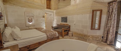 Une chambre à coucher avec une grande baignoire, un lit recouvert de draps blancs, une chaise en bois et une petite fenêtre.