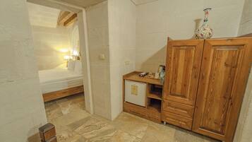 A bedroom with a bed, a nightstand, a wooden wardrobe, and a small cabinet.