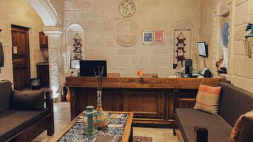 A cozy lobby with a reception desk, seating area, and decorative elements like a clock and wall art.