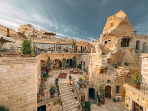 A hotel with a stone facade, multiple balconies, and outdoor seating areas. - Zara Cave Hotel +10 (Nevsehir)