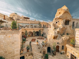 Un hotel con fachada de piedra, varios balcones y zonas de estar al aire libre.