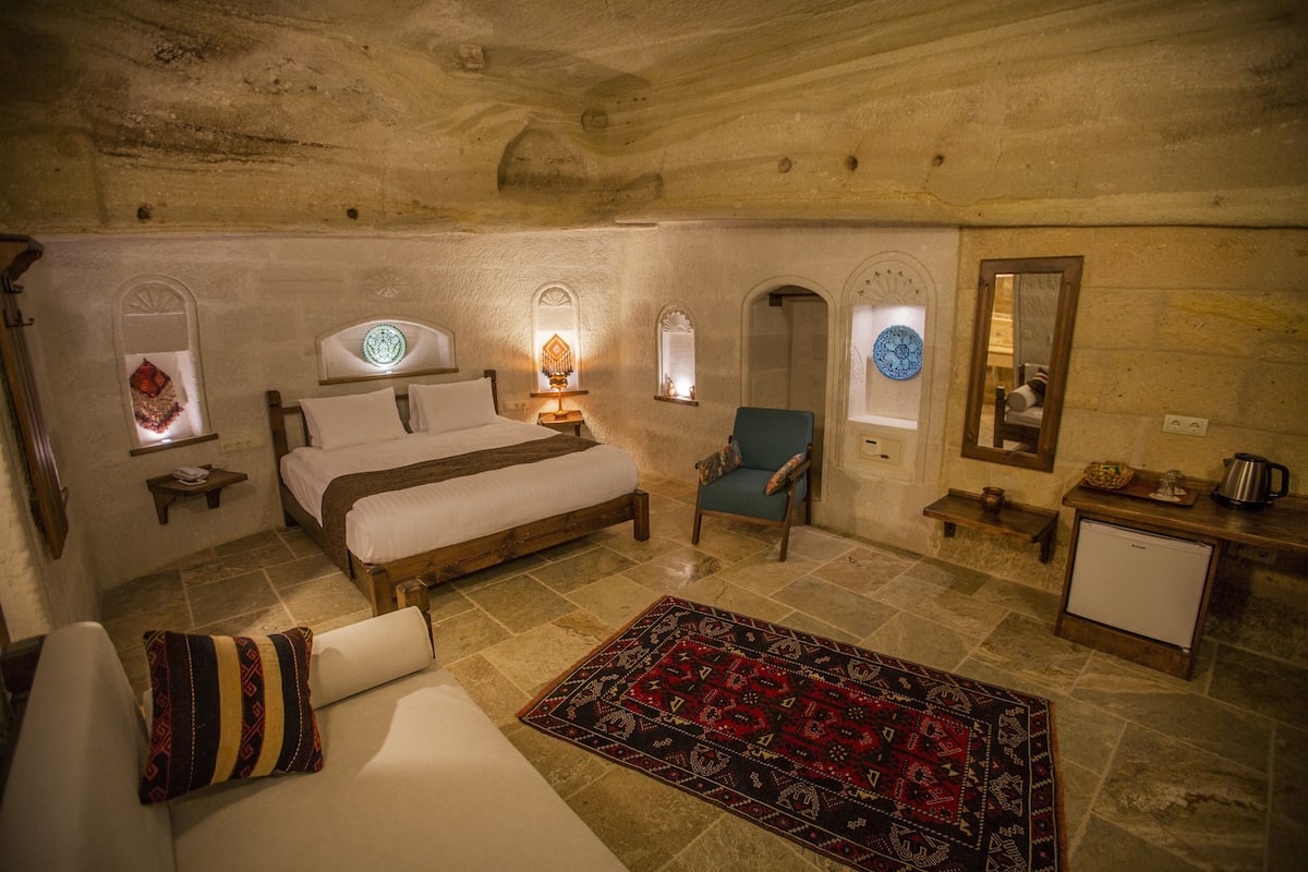 Une pièce confortable avec un lit, une chaise, une petite table et un réfrigérateur.