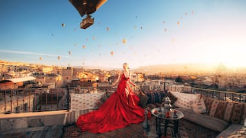 Relax on the rooftop with a panoramic view of the city, surrounded by plush furnishings and a decorative rug.