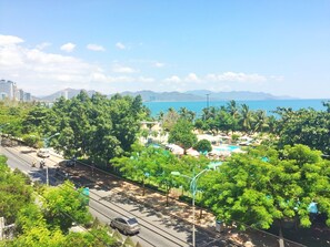 A coastal resort with a swimming pool, palm trees, and a view of the sea. - Anh Minh Manchester (Nha Trang)