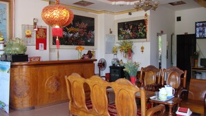 A traditional reception area with a wooden reception desk, a red lantern, and a painting of a fish. - Anh Minh Manchester (Nha Trang)