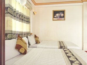 A hotel room with two beds, a decorative curtain, a wall-mounted light, and a framed floral painting. - Anh Minh Manchester (Nha Trang)