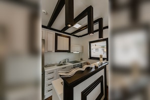 A modern kitchen with a dark wooden ceiling, white cabinets, and a large window. - Villa Varosh (Ohrid)