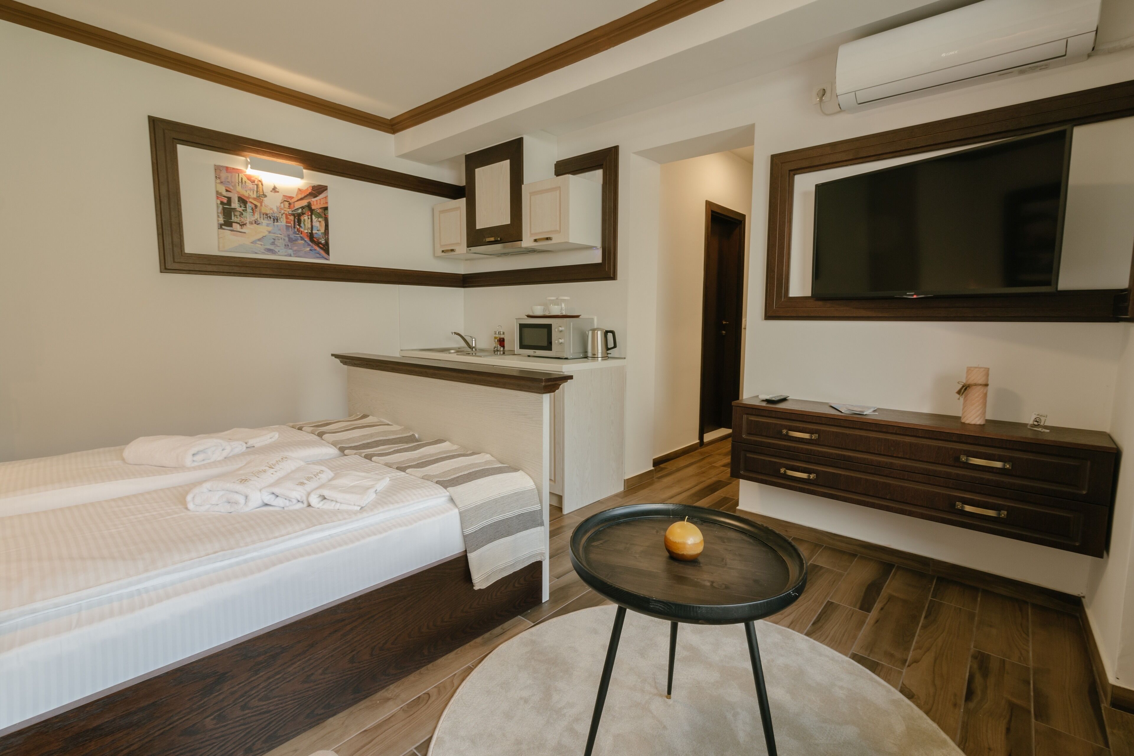 Una habitación de hotel con una cama, una mesita con una calabaza, un microondas y un televisor montado en la pared.