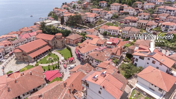 An aerial view of a coastal town with red-tiled buildings, a central courtyard, and a prominent tower. - Villa Varosh (Ohrid)