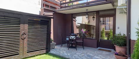 A patio with a stone floor, a table with chairs, and potted plants.