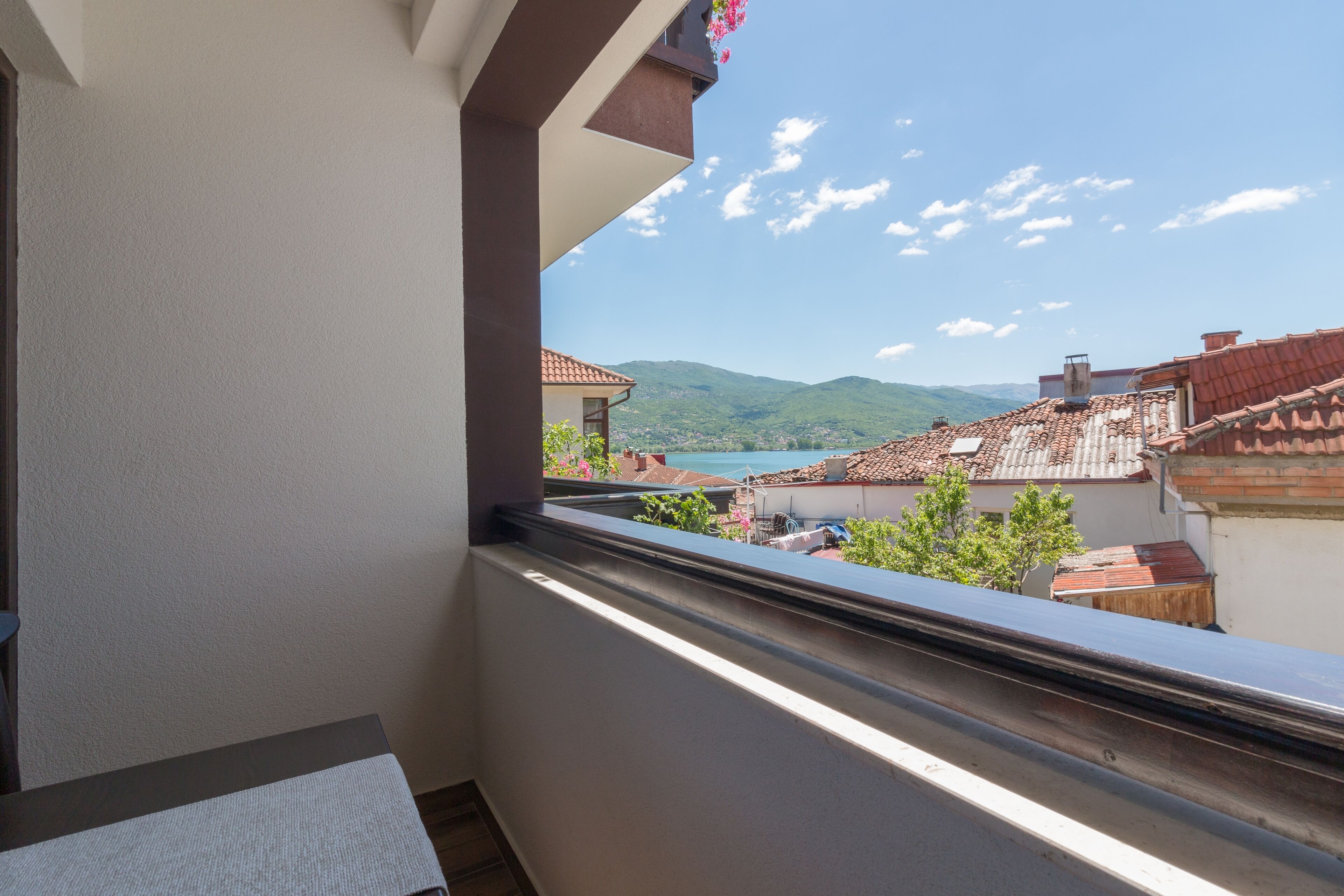 A balcony with a view of a mountainous landscape and terracotta-roofed buildings.