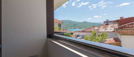 A balcony with a view of a mountainous landscape and terracotta-roofed buildings.