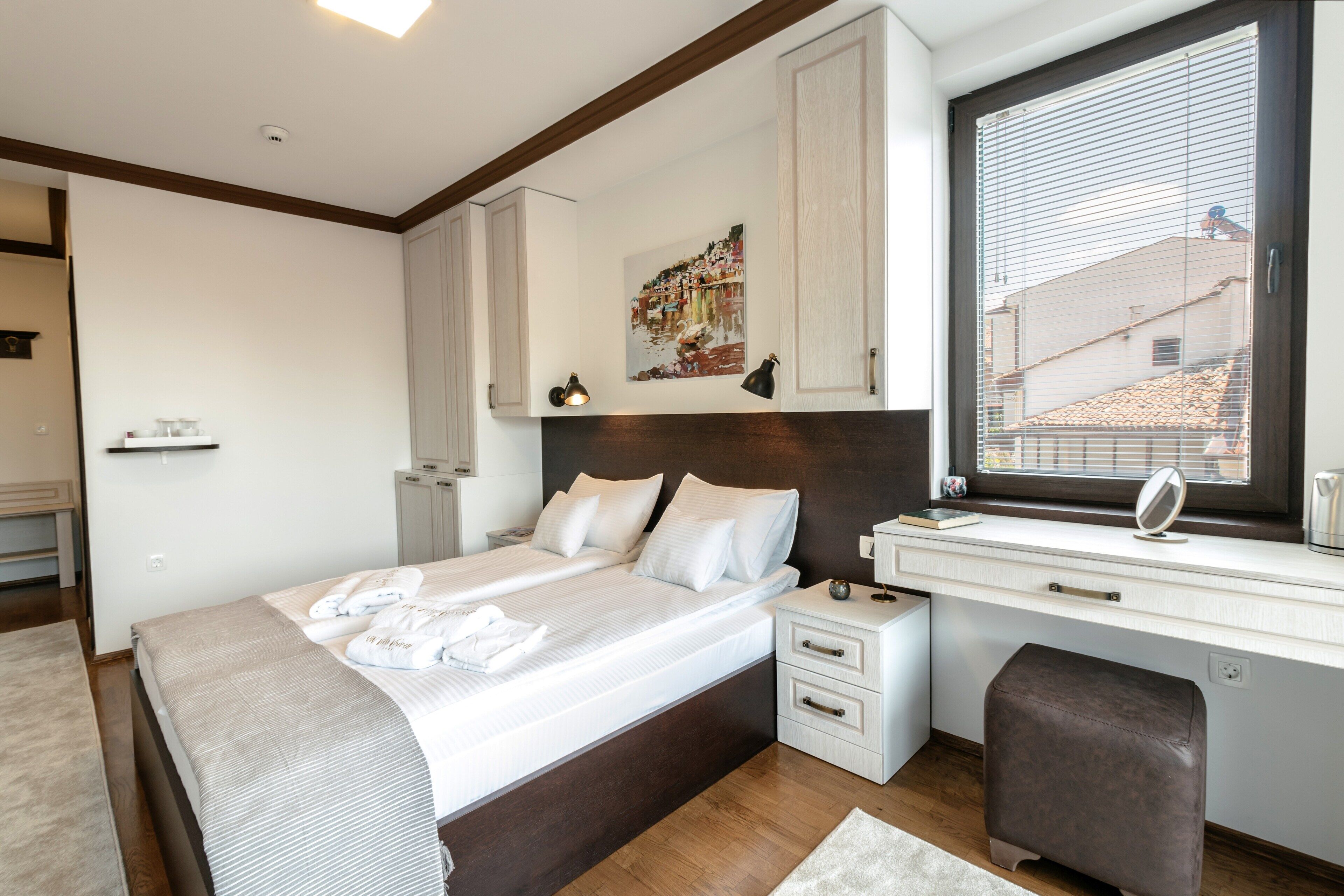 Un dormitorio moderno con una cama grande, mesitas de noche, un escritorio y una ventana con persianas.