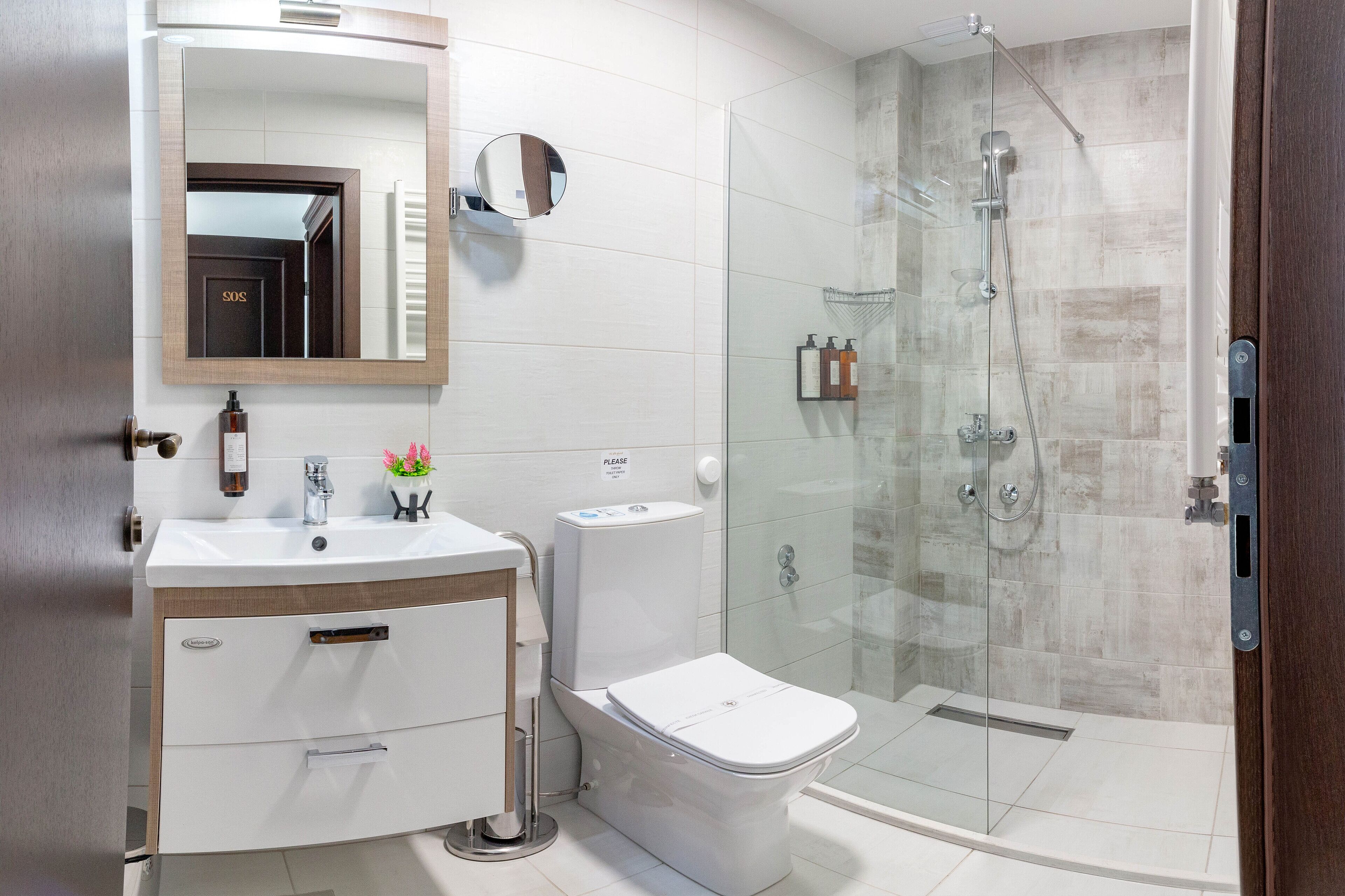 A modern bathroom with a glass-enclosed shower, a toilet, and a vanity with a mirror.