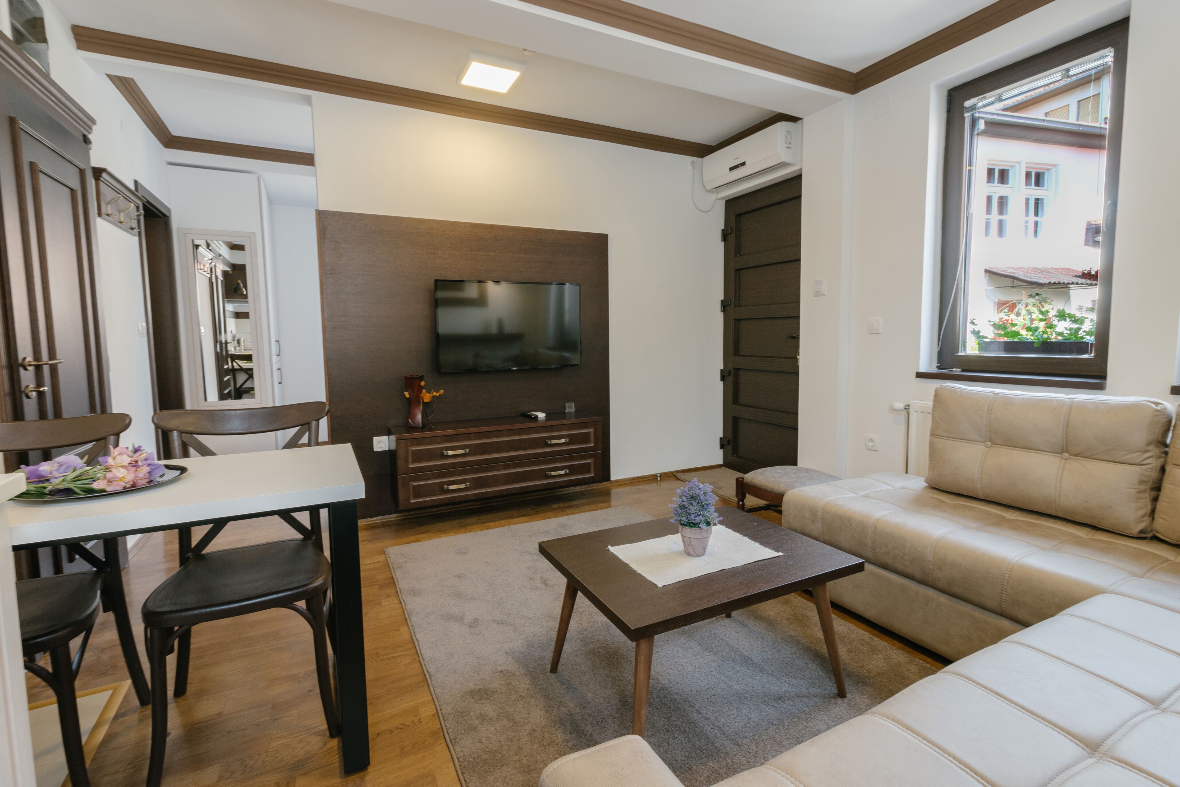 A living room with a sofa, a coffee table, a TV, and a dining area with chairs and a table.