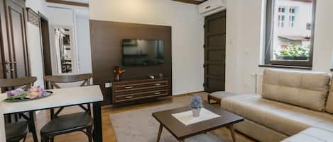 Una sala de estar con un sofá, una mesa de centro, un televisor y un comedor con sillas y una mesa.