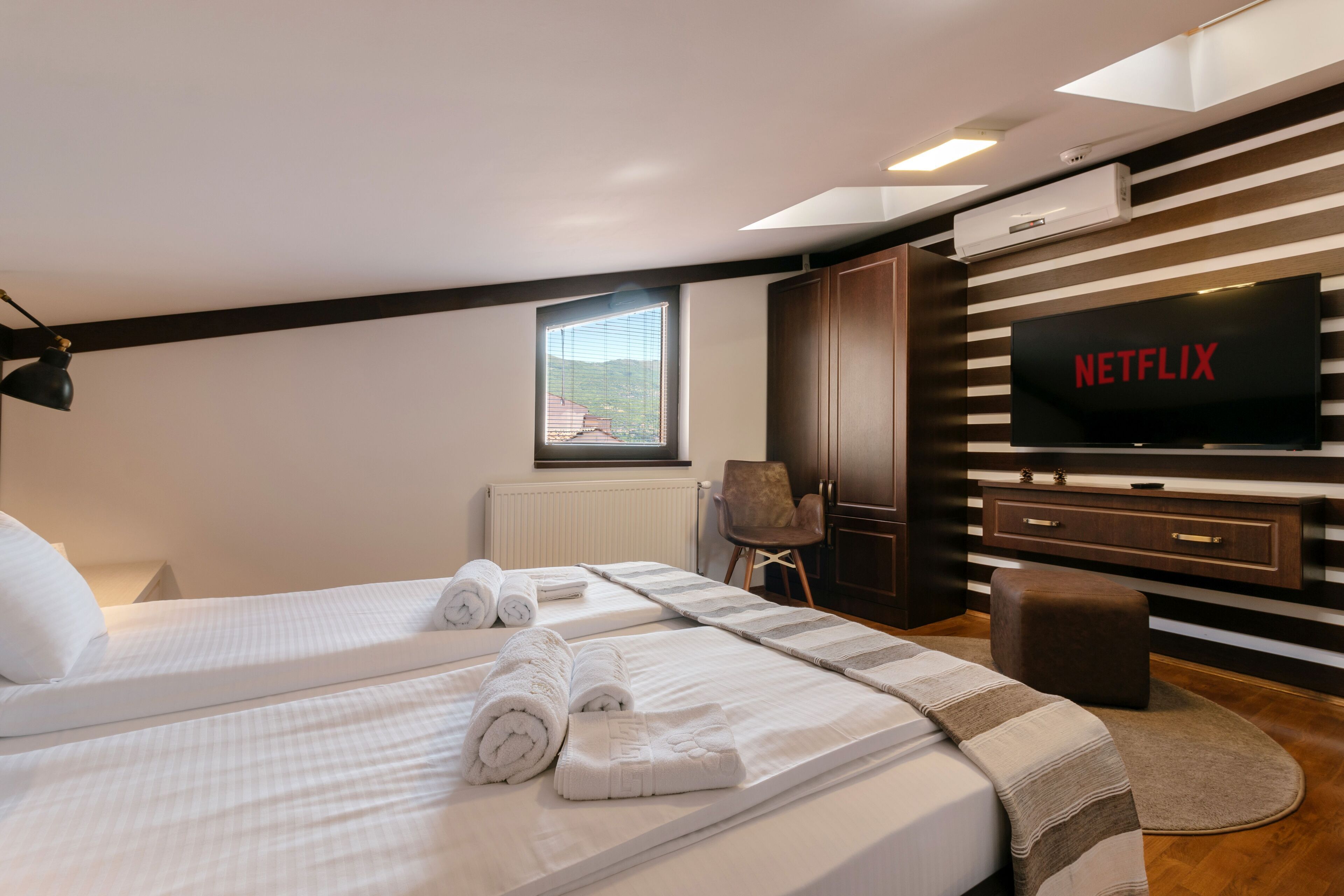 Habitación de hotel con dos camas, televisión, ventana y vistas al exterior.
