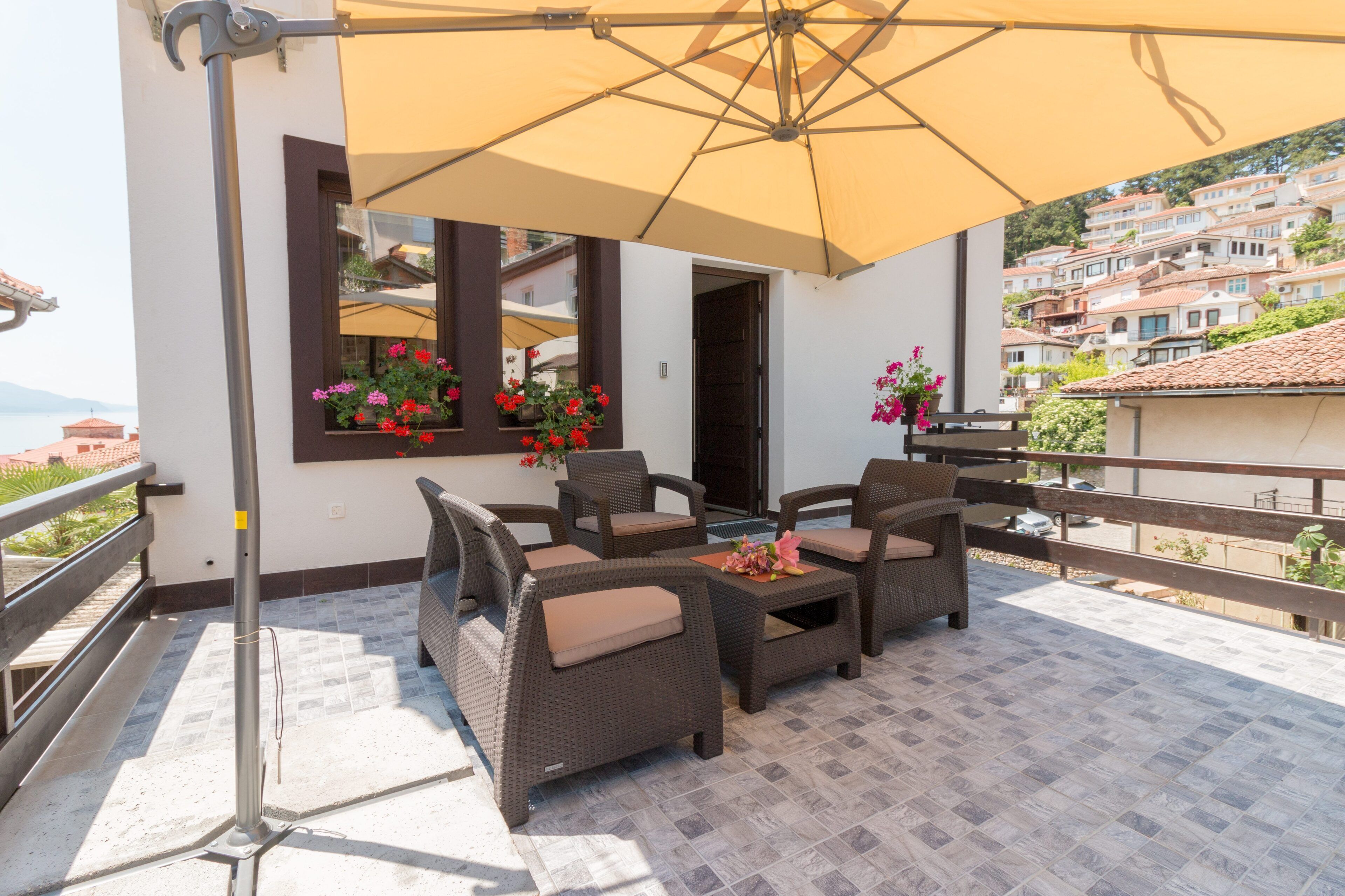 A balcony with wicker furniture, a large umbrella, and flower boxes.