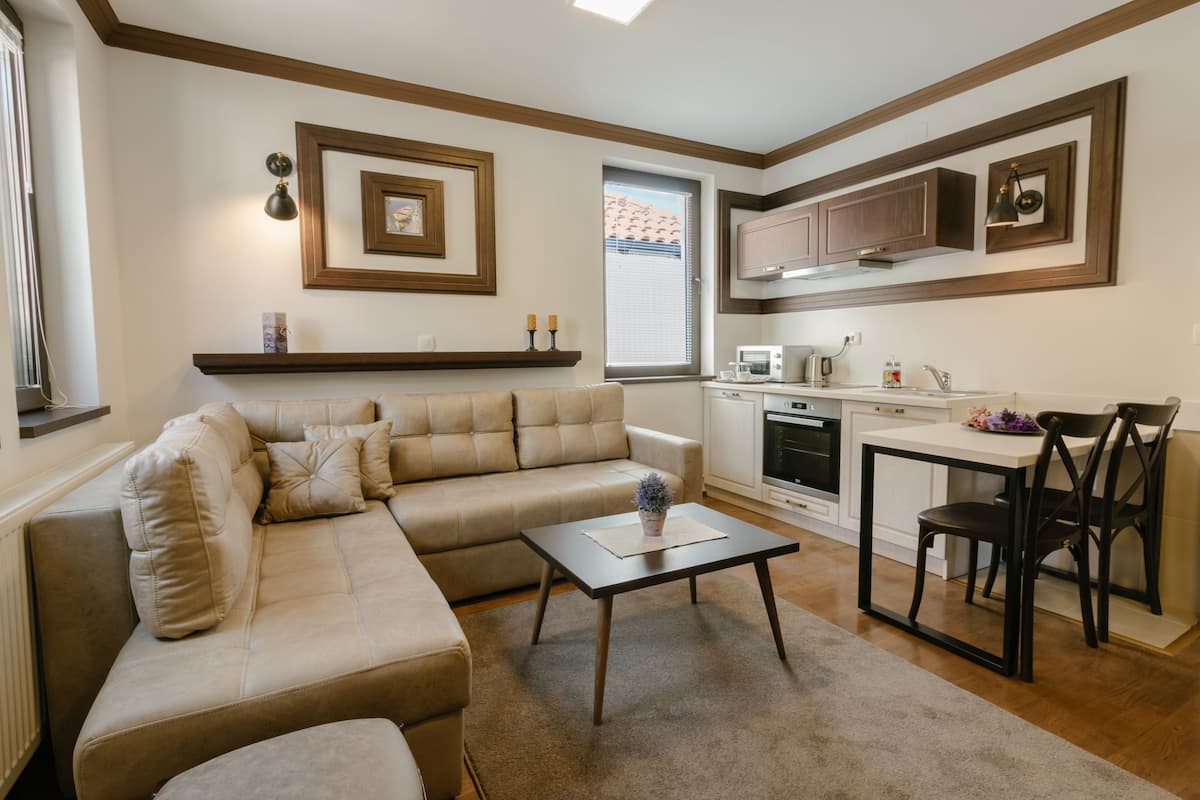 A modern living room with a beige sectional sofa, a small coffee table, and a dining area with a white table and two chairs.