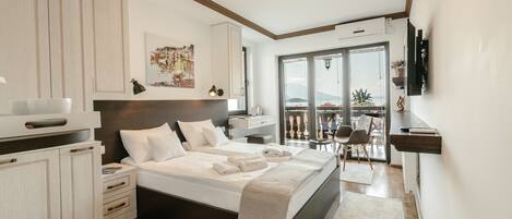 Un dormitorio moderno con una cama grande, mesitas de noche, un escritorio y un balcón con vistas.