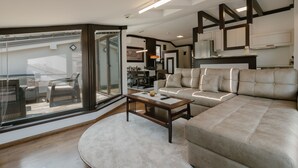 Una sala de estar moderna con un amplio sofá modular, una mesa de centro y un puerta de cristal que da a un patio exterior.