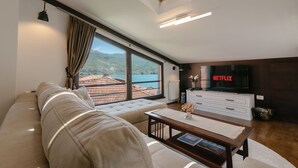 Una sala moderna con un sofá, una mesa de centro, un televisor y vistas al mar.