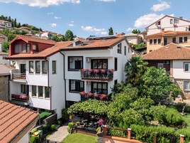 Un edificio de varios pisos con balcones, un jardín y vistas a edificios circundantes.