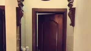 A bathroom with a wooden door, a sink, and a mirror. - Petra Villa (Wadi Musa)