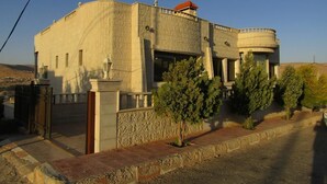A building with a curved facade, a small balcony, and a circular structure attached to the main building. - Petra Villa (Wadi Musa)