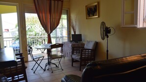 En stue med spiseplads, sofa, fjernsyn og ventilator.