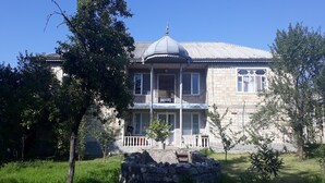 Un edificio de piedra con una cúpula central, un balcón y un muro de piedra al frente.