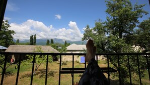 Un balcón con vistas a un paisaje rural, que incluye casas y montañas.