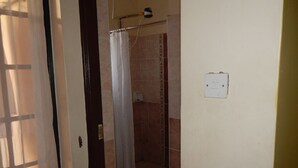 Une salle de bain avec une douche, un porte-serviettes et un interrupteur sur le mur.