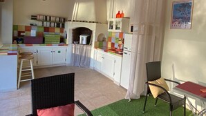 Een gezellige keuken met een houten plafond, een inbouwoven en een eethoek met rieten stoelen en een kleine tafel.