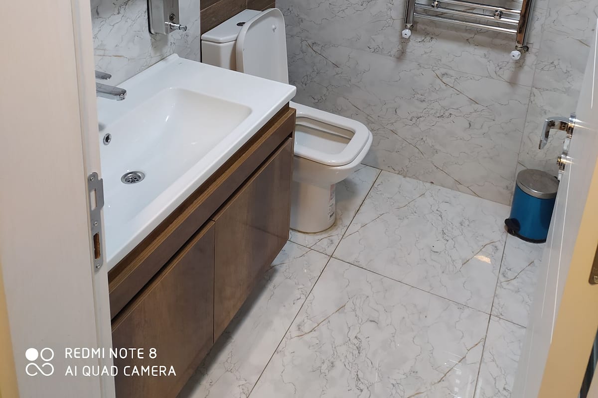 A modern bathroom with a marble sink, a toilet, and a towel rack.