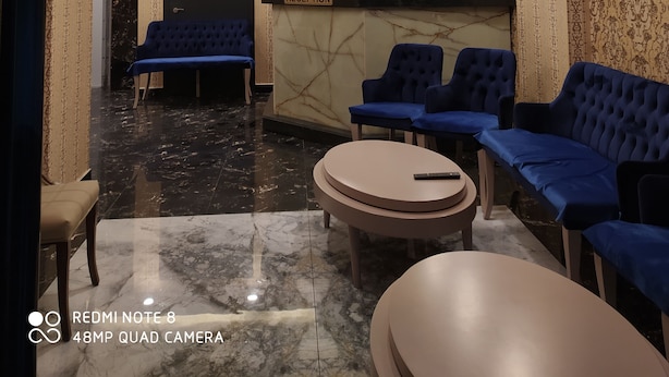 A hotel reception area with a marble floor, blue seating, and a reception desk. - Akdeniz Van Otel (Van)